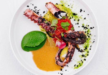 Elegantes Gericht aus gegrilltem Oktopus mit bunten Gemüsepürees und Gewürzen