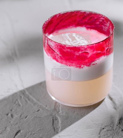 Téléchargez les photos : Cocktail élégant avec des couches roses et blanches vibrantes, présenté sur un fond moderne et texturé - en image libre de droit