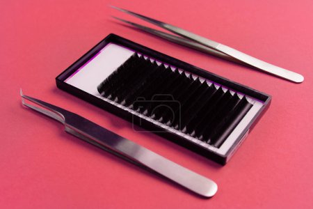 High-precision tweezers and eyelash strips for extensions, showcased on a vibrant red surface