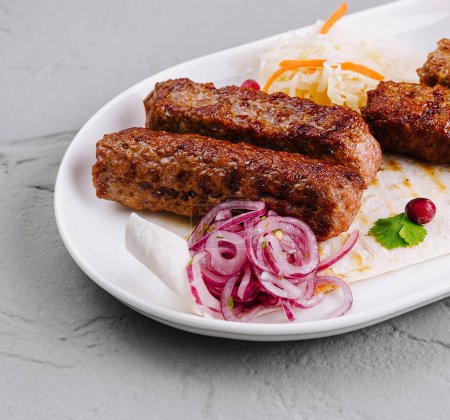 Juicy grilled kebabs served on a white plate with fresh salad and dipping sauce
