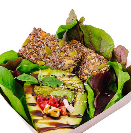 Nutritious vegan meal featuring avocado, mixed greens, and seed bars in a takeout box