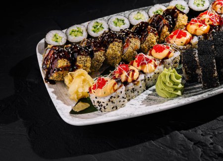 Luksusowy wybór bułek sushi serwowanych z wasabi i imbirem na eleganckim talerzu na ciemnym tle