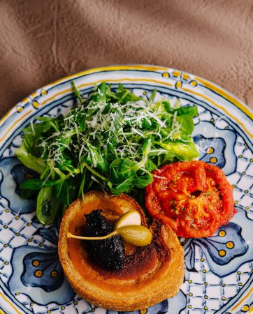 Elevated view of a delicious toast with tomato, greens, and spread on a designer plate
