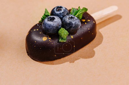 Handgemachte Eiscreme mit frischen Blaubeeren und Schokolade auf warmem, neutralem Hintergrund