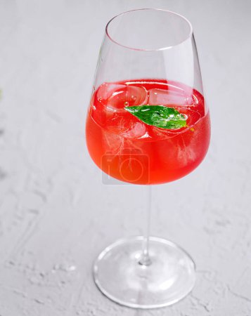 Téléchargez les photos : Élégant verre de cocktail d'été rouge vif orné de menthe fraîche sur une surface texturée - en image libre de droit