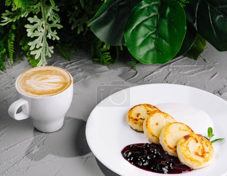 Delicious crepes with berry syrup accompanied by cheese pancakes and a cup of coffee