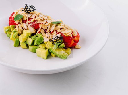 Frischer Avocadosalat mit Paprika und Nüssen und Mandelsplittern auf einem weißen Teller
