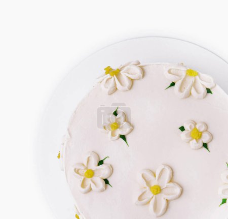 Top view of a beautifully decorated cake with white frosting and edible flowers