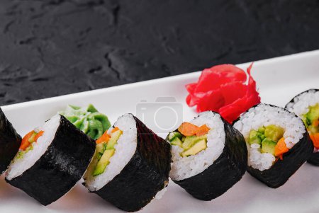 Sushi-Auswahl mit frischen Zutaten auf einem modernen weißen Teller vor dunklem Hintergrund