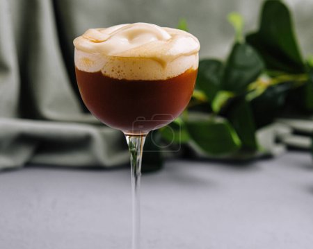 Espresso martini with a creamy foam topping, presented in a stemmed glass against a neutral background