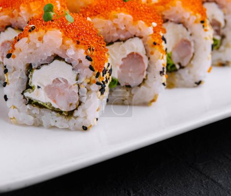 Close-up of delicious california rolls adorned with fish roe, served with wasabi and ginger