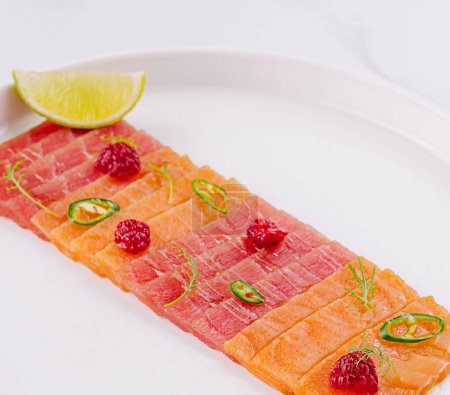 Élégante présentation de sashimi au saumon garni de lime et d'herbes sur une assiette blanche