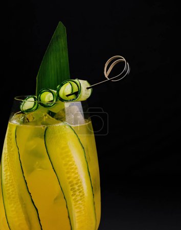 Prise de vue artistique d'un cocktail infusé de concombre avec garniture sur fond noir