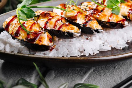 Fresh mussels with herbs and sauce served on a bed of rice, with green foliage backdrop
