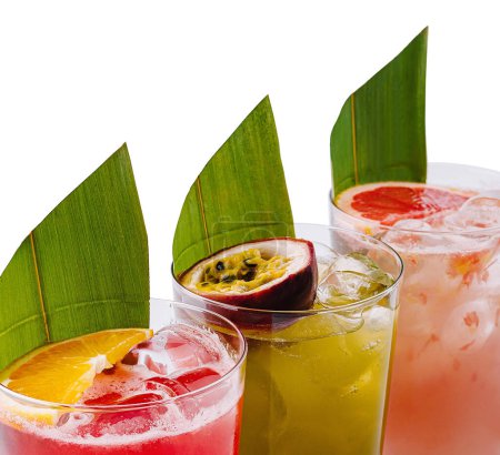Tres coloridas bebidas tropicales adornadas con rebanadas de frutas y hojas sobre un fondo blanco
