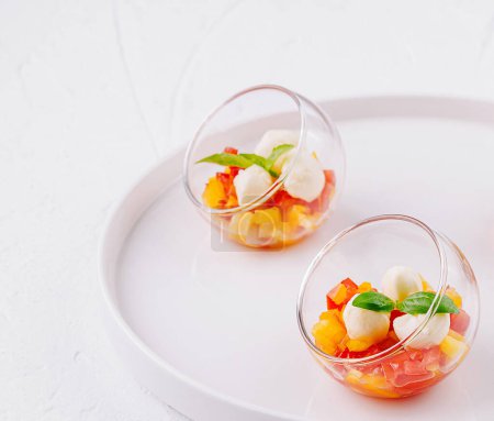 Moderna presentación de ensalada de frutas servida en cuencos de vidrio transparente sobre un plato blanco