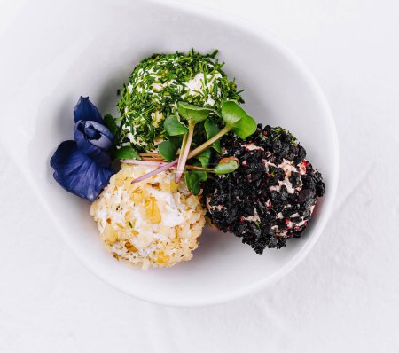 Foto de Trío de bolas de queso recubiertas de varias hierbas servidas en un plato elegante, aisladas sobre fondo blanco - Imagen libre de derechos