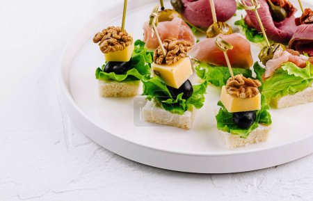 Foto de Elegante surtido de canapés con queso, frutos secos y carnes curadas, perfectos para catering y eventos - Imagen libre de derechos