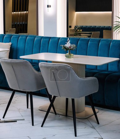 Elegant cafe interior showcasing a chic blue velvet sofa, marble flooring, and sophisticated lighting