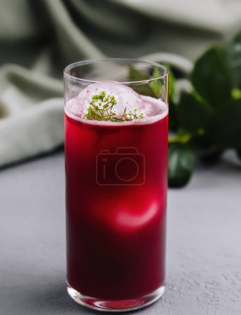 Elegant red cocktail garnished with herbs in the foreground