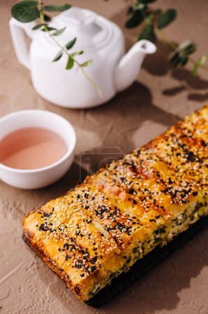 Pan recién horneado espolvoreado con semillas de sésamo, servido con té caliente