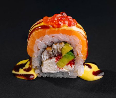 Smakosz sushi roll zwieńczony łososia i jasnoczerwony kawior na ciemnym tle