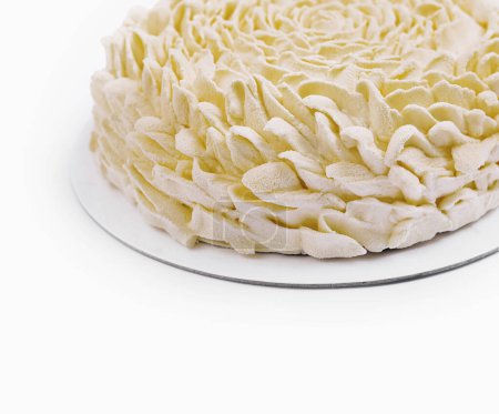 Beautifully piped white buttercream rosette cake on a simple round stand against a white background