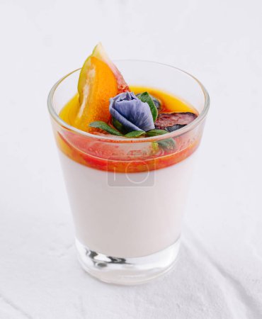 Elegant dessert of panna cotta with colorful fruit topping on a white backdrop