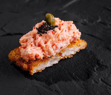 Elegant salmon tartare on a crispy rice base, garnished with capers, perfect for fine dining menus