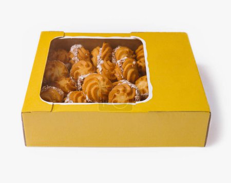 Vibrant yellow box filled with delicious moldovan pastry cookies, isolated on a white background