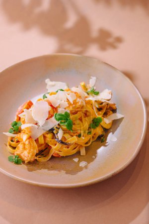 Elegant serving of tagliatelle pasta with shrimp, mushrooms, and shaved parmesan cheese garnished with fresh herbs