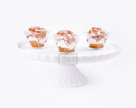 Weißer Podest-Kuchenstand mit drei handwerklichen Cupcakes mit zartem Zuckerguss vor sauberem Hintergrund
