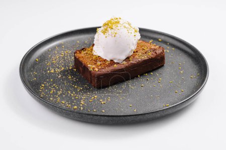 Elegant chocolate brownie topped with a scoop of vanilla ice cream and gold dust served on a black plate