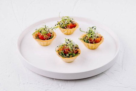Des canapés élégants avec des tomates juteuses et des microverts délicats sur une assiette blanche