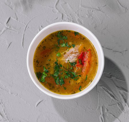 Top view of a delicious bowl of savory soup with herbs, ideal for healthy eating concepts