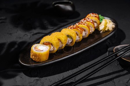 Verlockende Mango-Sushi-Rolle, serviert auf einem schicken schwarzen Teller, perfekt für kulinarische Themen