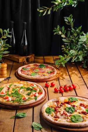 Artisanal pizzas with fresh toppings and wine bottles on a dark, rustic setting