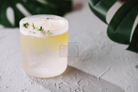 Chilled cocktail with herbal garnish placed elegantly on a textured grey background