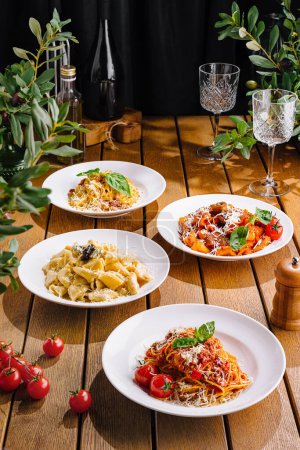Surtido de platos de pasta bellamente presentados en un ambiente cálido, mesa de madera, evocando un ambiente acogedor comedor italiano
