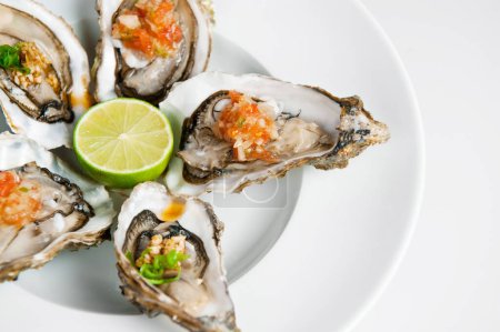 Appetizing plate of raw oysters garnished with lime and salsa on a white background
