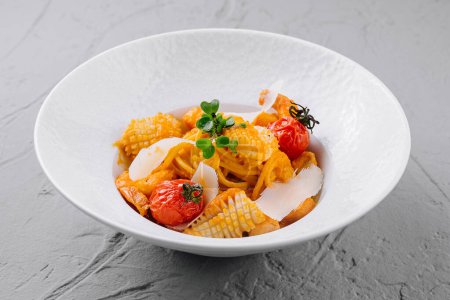 Exquisita pasta con tomates cherry asados, hierbas y parmesano en un tazón blanco, buena comida