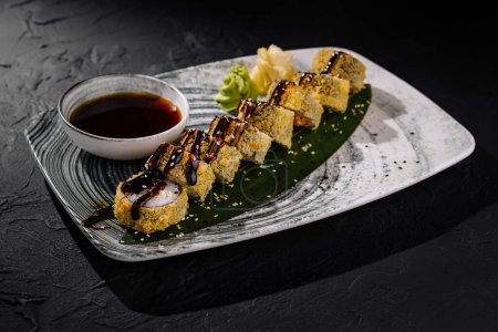 Smakosze sushi bułki ozdobione sezamem, serwowane z sosem sojowym, imbirem i wasabi na ciemnym łupku