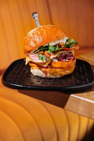 Nahaufnahme eines Deluxe-Burgers auf einem stilvollen Teller mit warmfarbigem Hintergrund