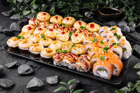 Variety of sushi rolls presented on a slate with garnishing, perfect for japanese cuisine concepts