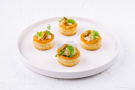 Exquisite puff pastry cases filled with savory filling, garnished with herbs on a sleek plate