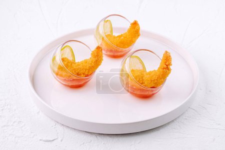 Elegant shrimp cocktail appetizers served in glasses on a stylish white plate, suitable for upscale events
