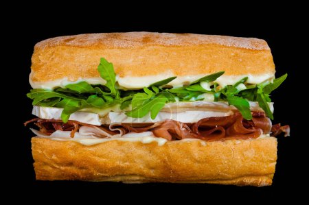 Delicious turkey sandwich with arugula and cheese on a crusty roll against a dark backdrop
