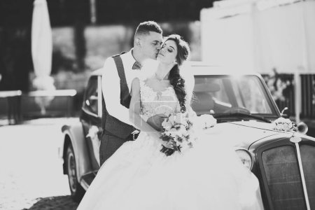 Photo for Wedding bride and groom, elegant couple staying near retro wedding car. - Royalty Free Image