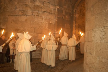 Photo for Holy Week procession of Zamora, Spain on the night of Holy Monday of the Penitential Brotherhood of the Holy Christ of Good Death. Penitents with torches procession in the dark night through the old town. - Royalty Free Image