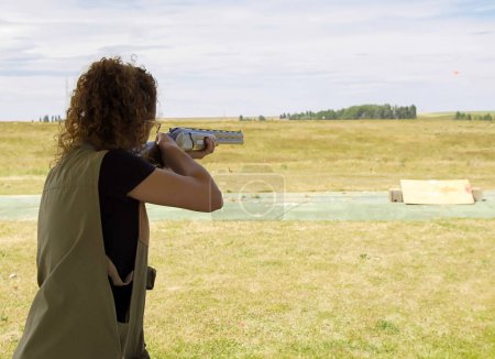 Foto de Mujer con un rifle disparando al aire libre durante una competición de tiro. - Imagen libre de derechos